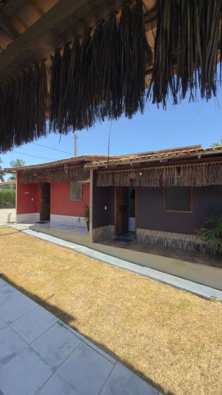 a red building with a thatched roof at Pousada Villa Maria Corumbau in Corumbau