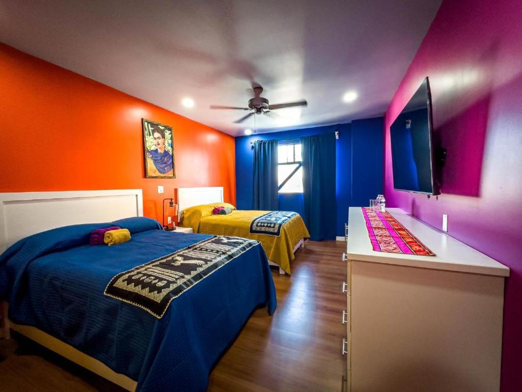 two beds in a room with orange and blue at Hotel Los Cantaros in Rosarito Beach