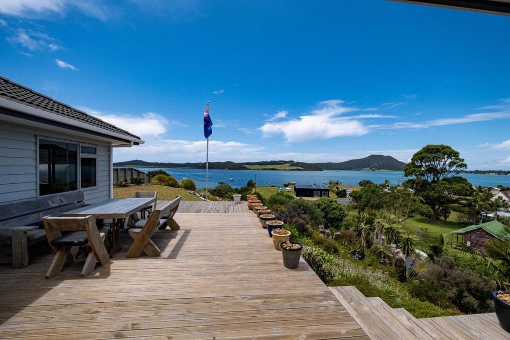 a wooden deck with a picnic table and a view of the water at Hook'em Heights in Pukenui