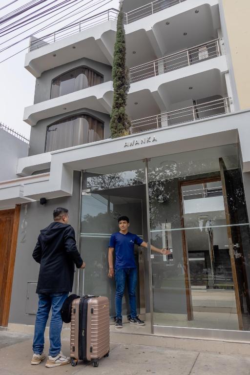 two men with luggage standing outside of a building at San Miguel Awanka Hotel in Lima