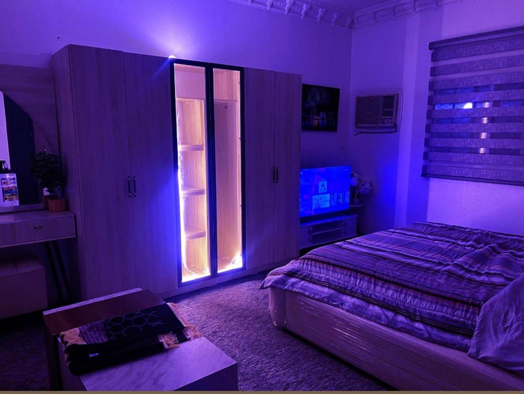 a bedroom with a bed and a purple light at استوديو 104 in Tabuk