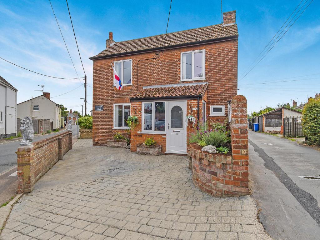 a brick house with a white door on a street at Ravensmere Villa in Beccles