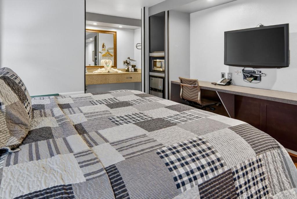 a bedroom with a bed and a desk with a television at 12 Oaks Hotel in Tyler