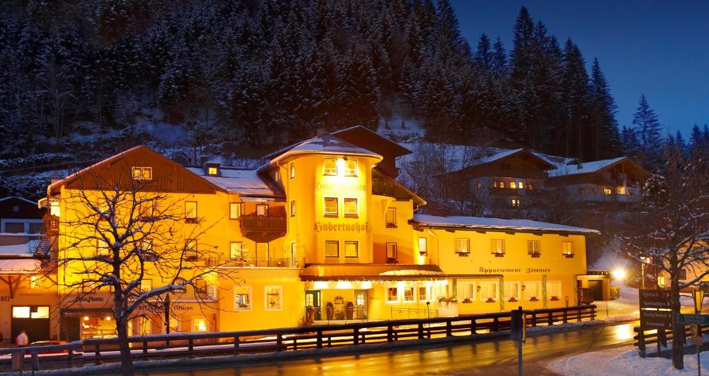 a large yellow building in the snow at night at Hotel Hubertushof in Flachau