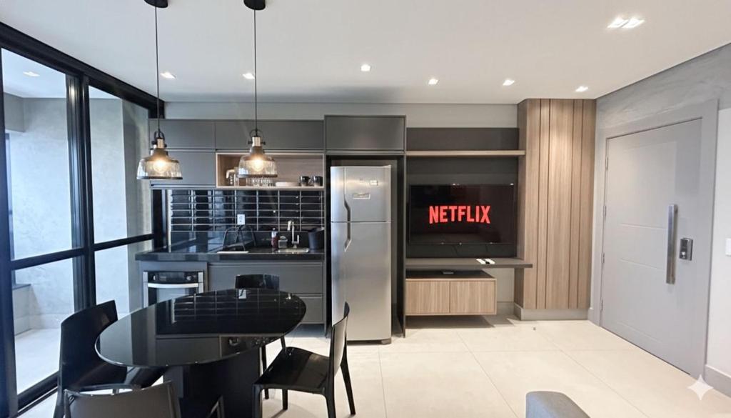 a kitchen with a table and a refrigerator at Lindo Studio Com Vista para Cidade in Campo Grande