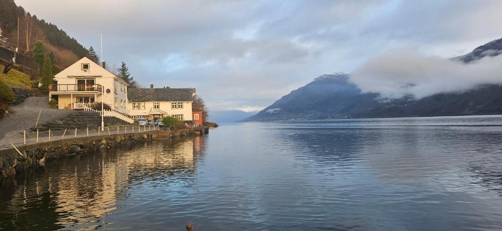 a house on the side of a lake with mountains at Hardanger Fjordblikk in Syreflot