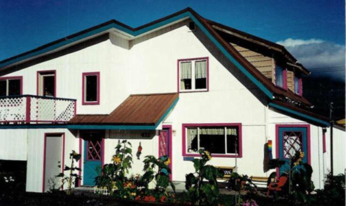 a white house with red doors and a balcony at MobyDick Hostel in Seward
