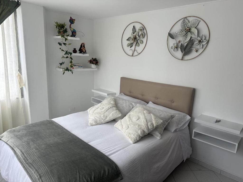 a bedroom with a bed with two plates on the wall at Siga Sumercé Apartamento completo centro de Duitama in Duitama