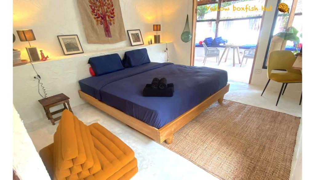 a bedroom with a large bed with blue sheets at Yellow Boxfish Hut in Ban Thong Phlu