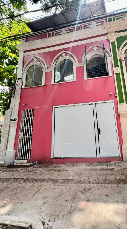 a red building with two white garage doors at Hostel Cünhatã in Belém