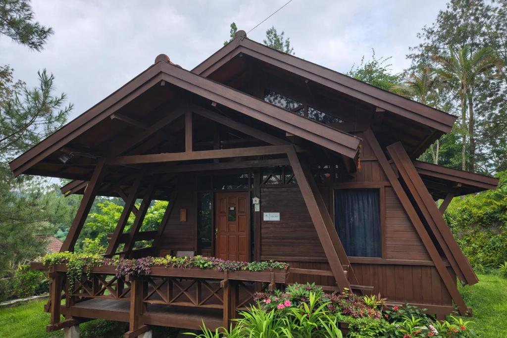a cabin in the woods with a porch and flowers at Villa Argapuri Hills in Ciwidey