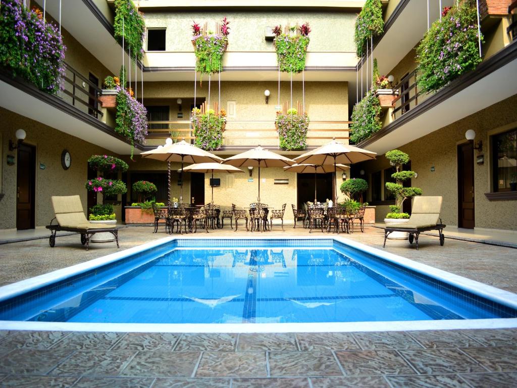 a pool in the courtyard of a hotel with tables and umbrellas at Hotel Layfer del Centro, Córdoba, Ver in Córdoba