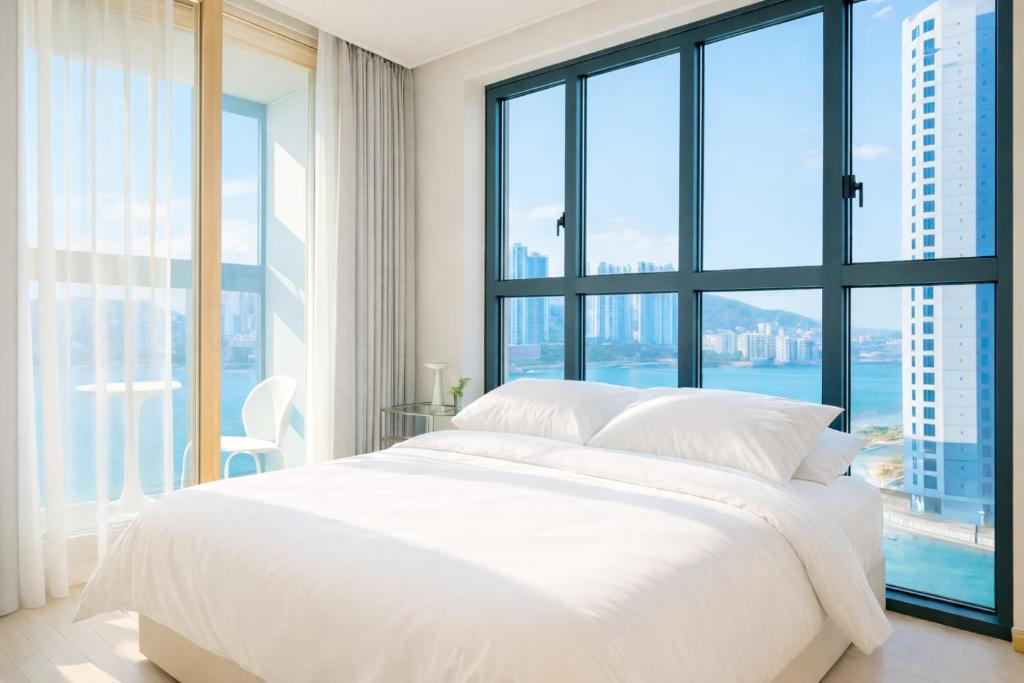a white bed in a room with large windows at 부산 엘스테이 호텔 레지던스 EL STAY Busan Long Stay Hotel Residence l 아르떼20 OFF짚라인30 OFF스릴10 OFF 할인 in Busan