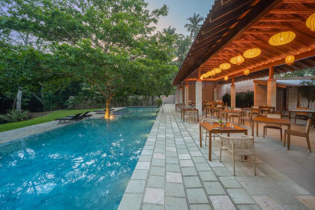 a swimming pool with tables and chairs next to a building at Cascara Resort Weligama - A Tropical Sanctuary in Weligama