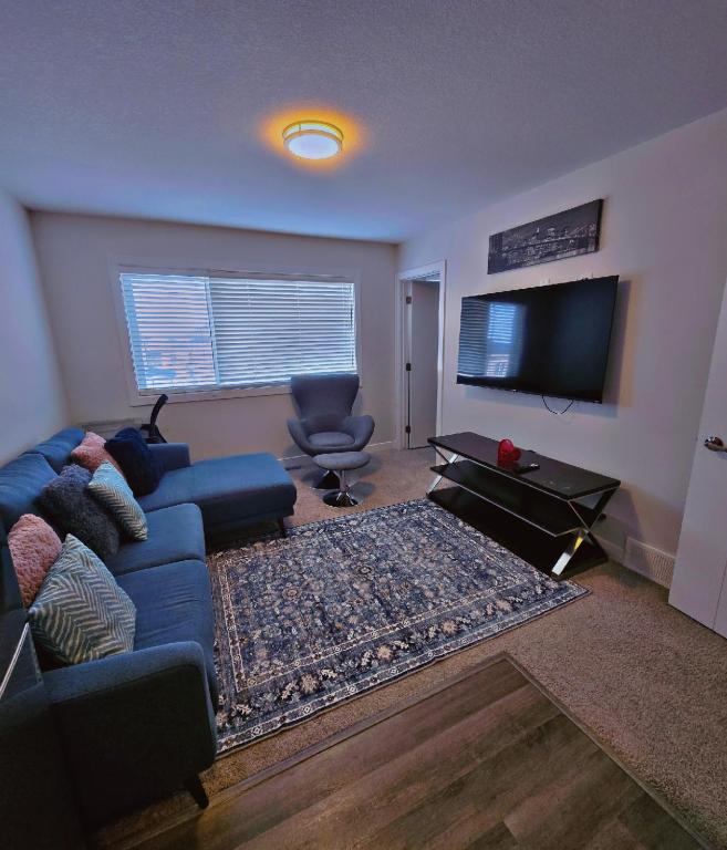 a living room with a blue couch and a flat screen tv at Atare Suite in Saskatoon