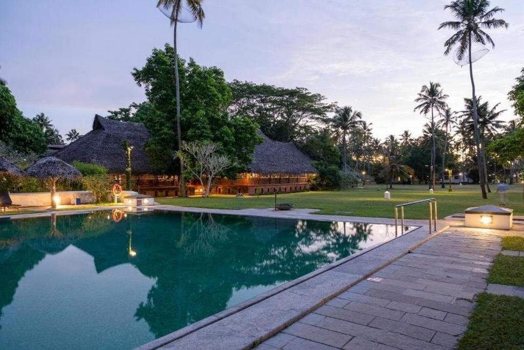 a swimming pool in front of a resort at Marari Beach Resort Alleppey - A CGH Earth Experience in Alleppey