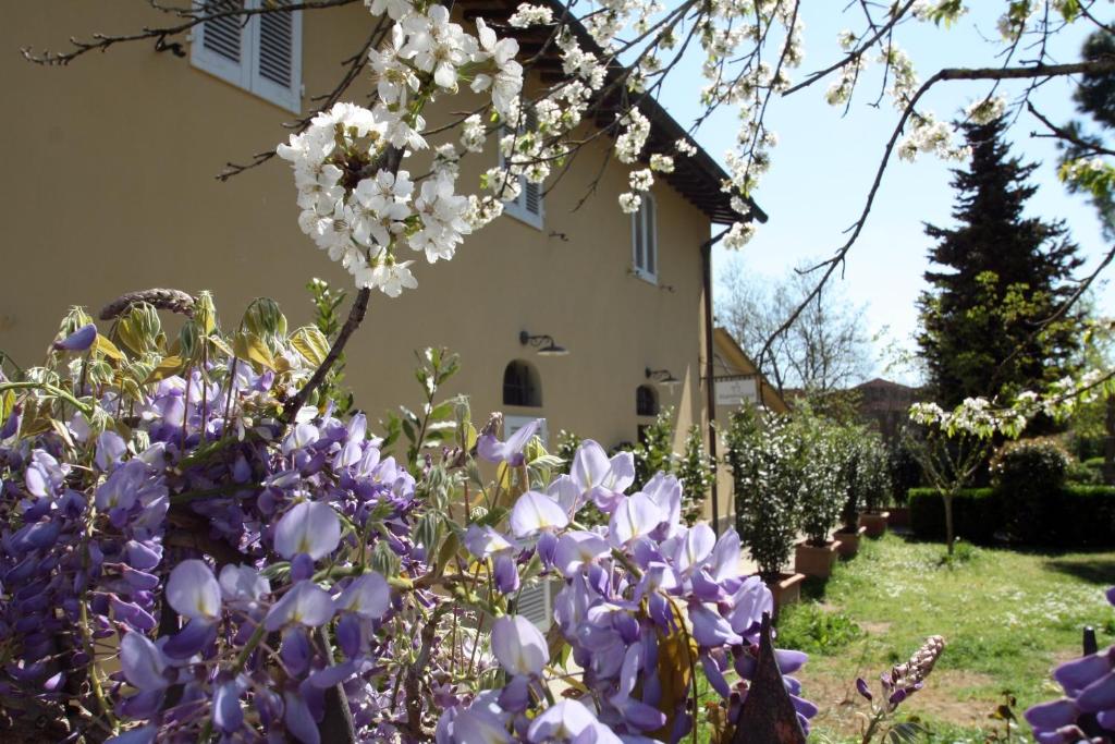 un giardino con fiori viola e bianchi di fronte a una casa di Hotel Calzaiolo a San Casciano in Val di Pesa