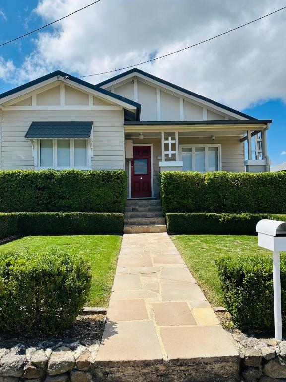 a white house with a red door at Alvane Cottage in Goulburn