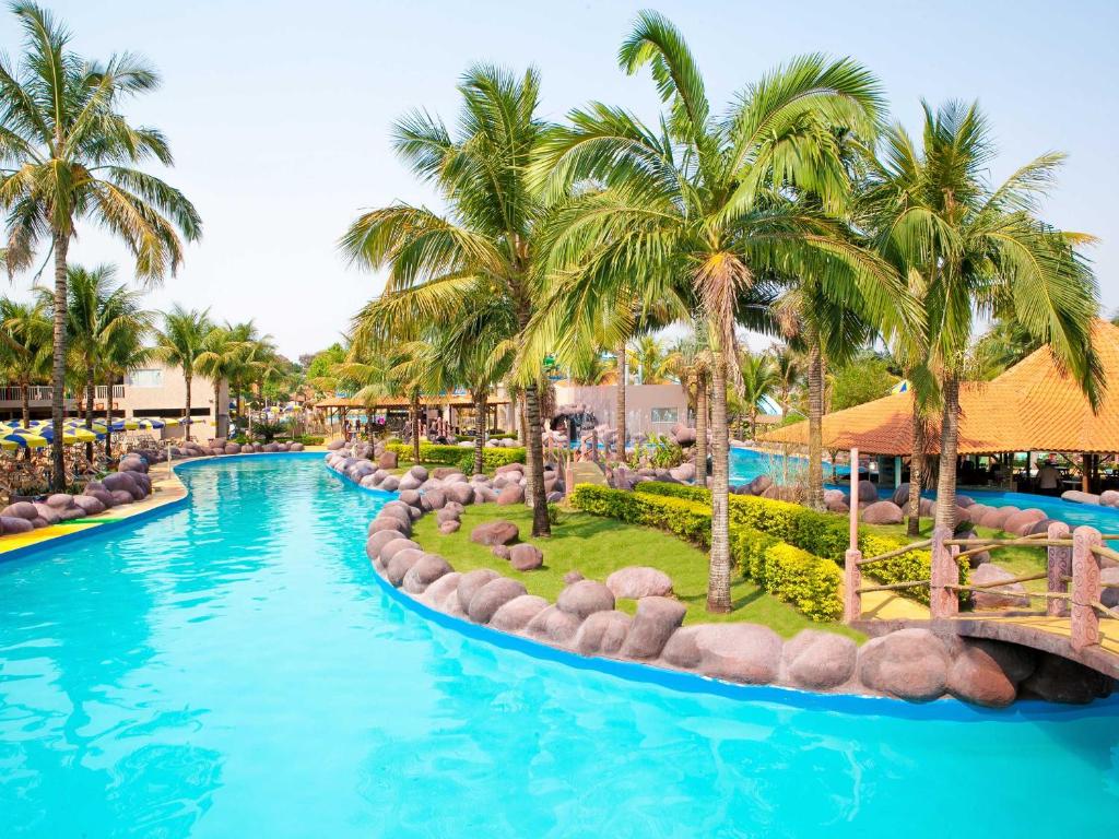 a pool at a resort with palm trees at Ody Park Resort Hotel in Iguaraçu