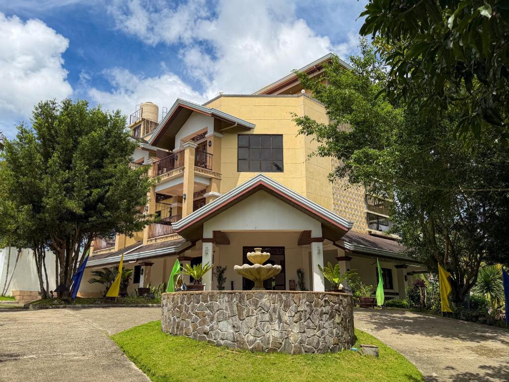 a yellow house with a fountain in front of it at Hotel Grand Luis in Dauis