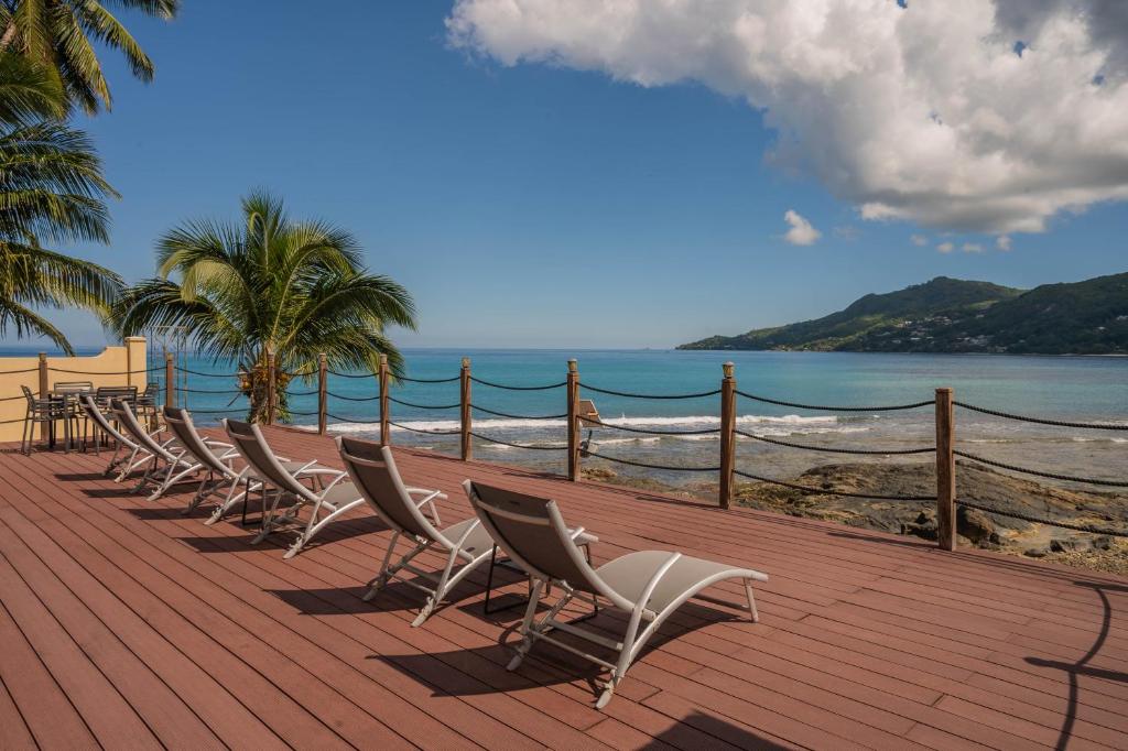 a row of chairs sitting on a deck near the beach at Surfers Cove Apartments in Bel Ombre