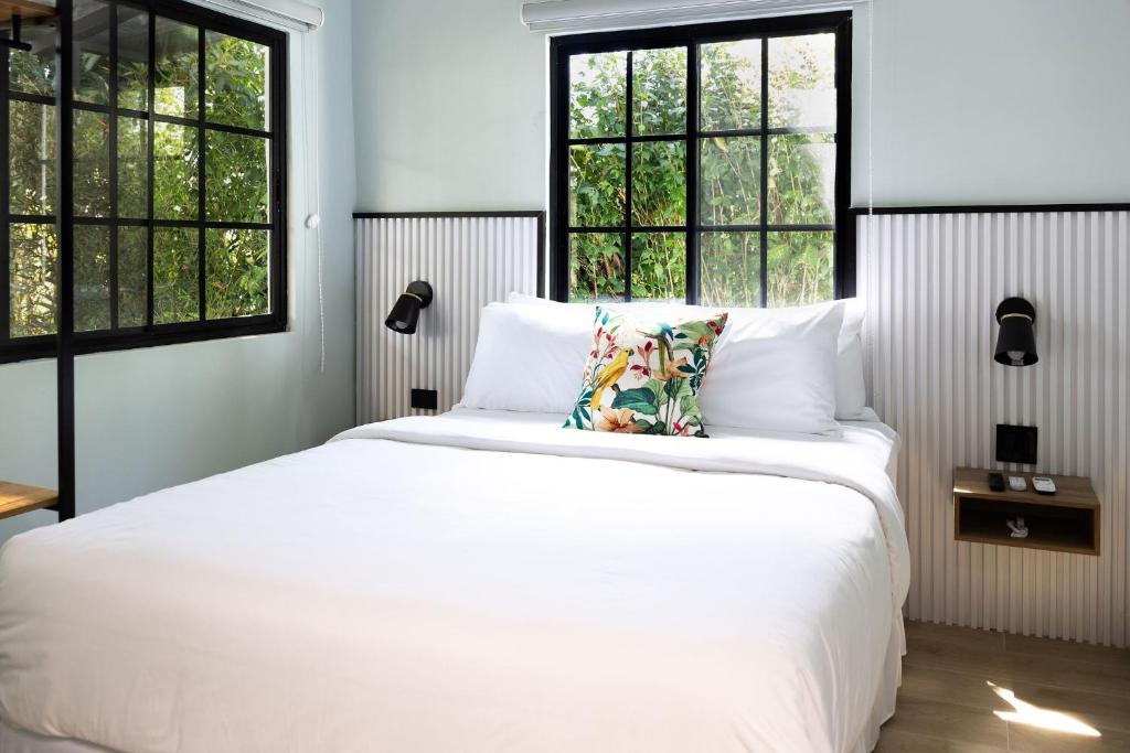 a bedroom with a white bed and two windows at Altavida Lodge Brand New Studio with Pool in El Valle in Valle de Anton