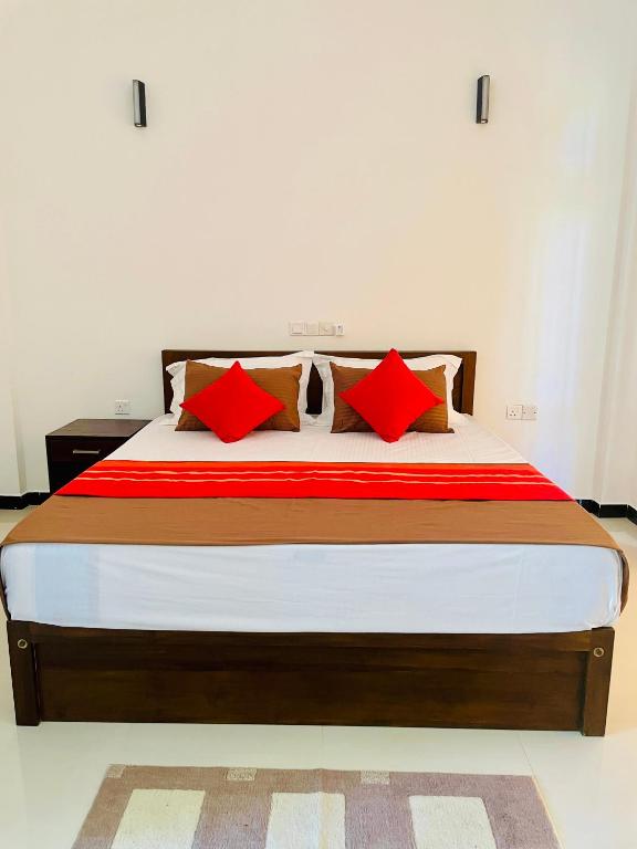 a bedroom with a large bed with red pillows at Ayubowan Yala in Tissamaharama