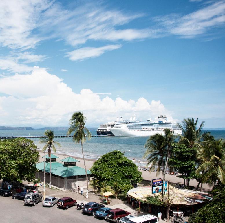 a cruise ship in the ocean with cars parked on the beach at Hotel Puntarenas Beach in Puntarenas