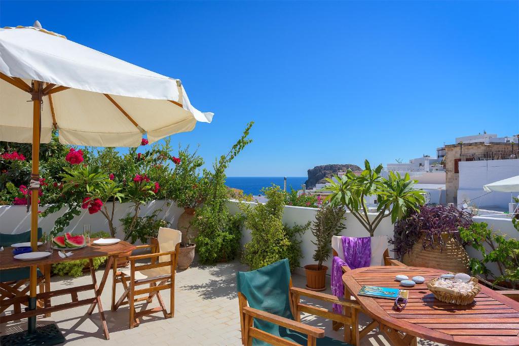 a patio with tables and an umbrella and the ocean at Erato Apartments in Líndos