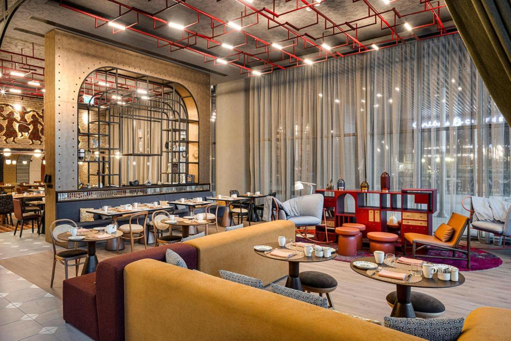 a restaurant with couches and tables and chairs at Canopy By Hilton Izmir Bomonti in İzmir