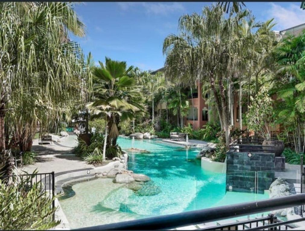 a pool in a resort with blue water and palm trees at Tropical Resort with balcony overlooking pool in Westcourt