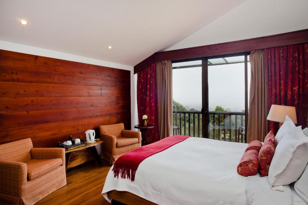 a bedroom with a large bed and a balcony at Poas Volcano Lodge in Vara Blanca