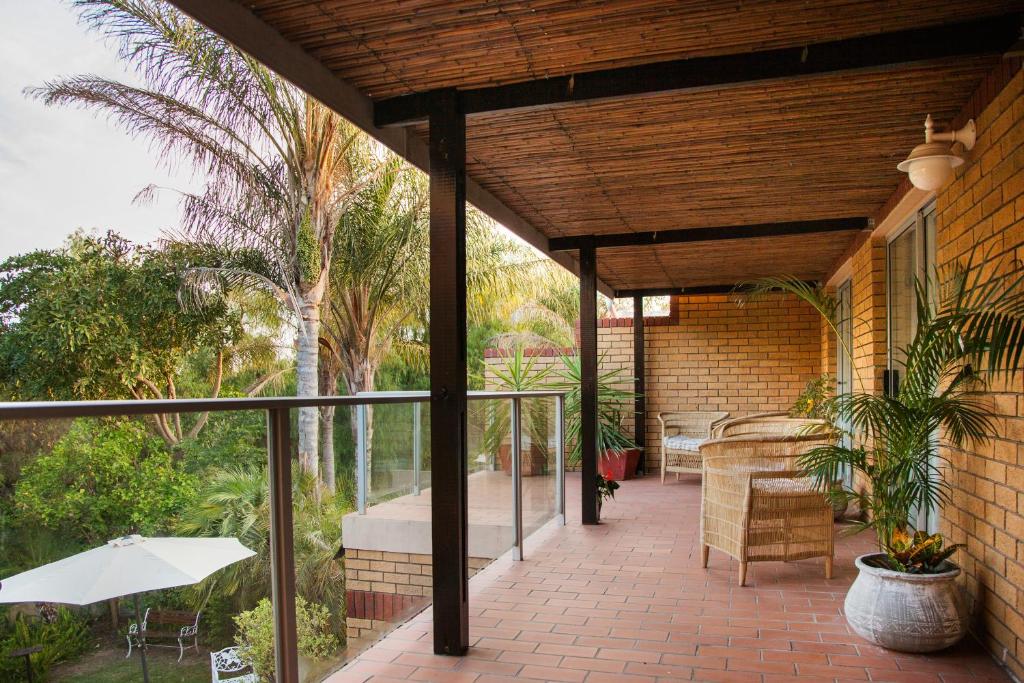 an outdoor patio with an umbrella and a table and chairs at Feather Nest Guest House in Oudtshoorn