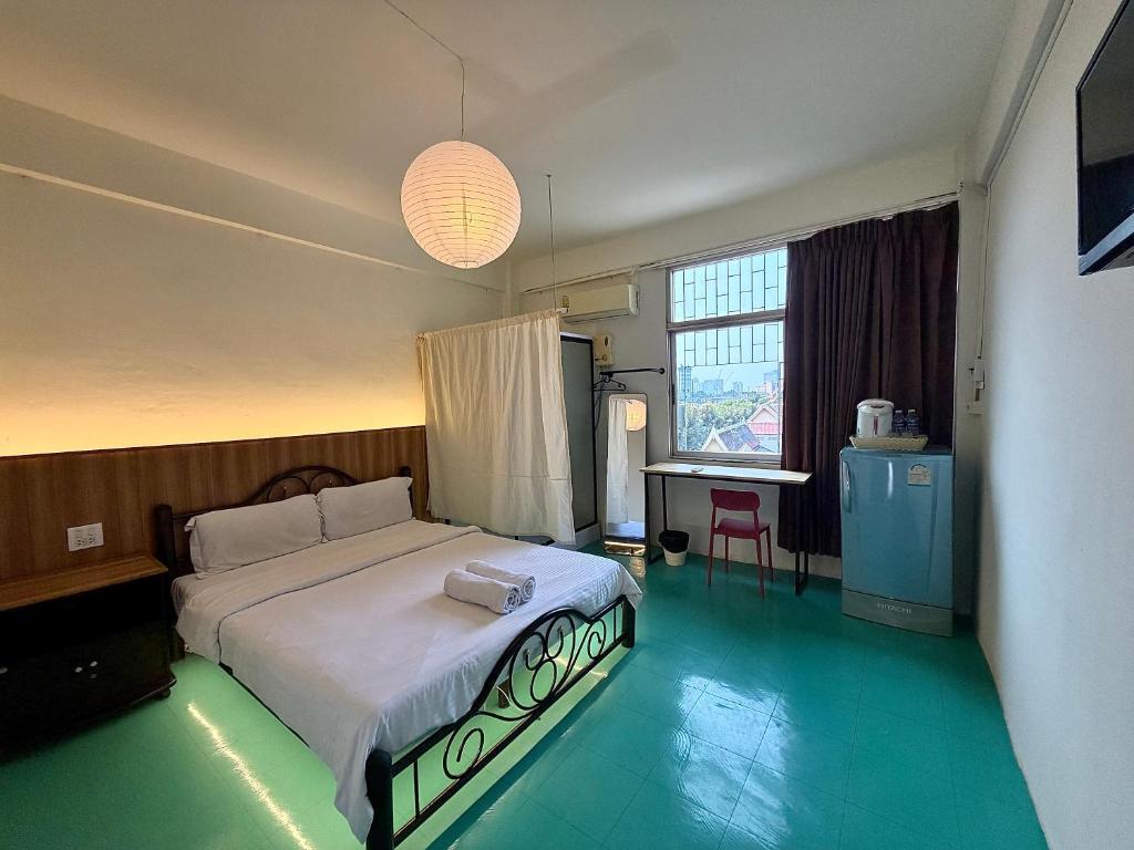a bedroom with a bed and a table and a window at arakhouse อารักษ์เฮ้าส์ in Godown