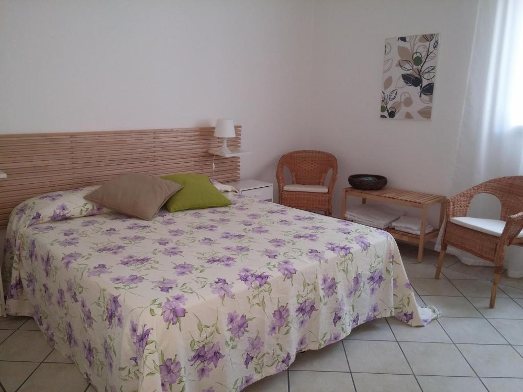 a bedroom with a bed with a floral bedspread and chairs at Akron B&B in SantʼAlessio Siculo