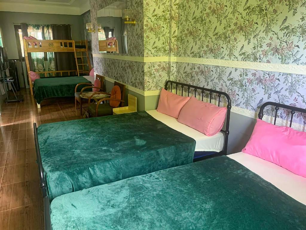 two beds in a room with green and pink at THE OASIS RESORT CondoBimbo 1-Big Room, Balcony, kitchen, Pool, Wifi, Videoke in San Fernando