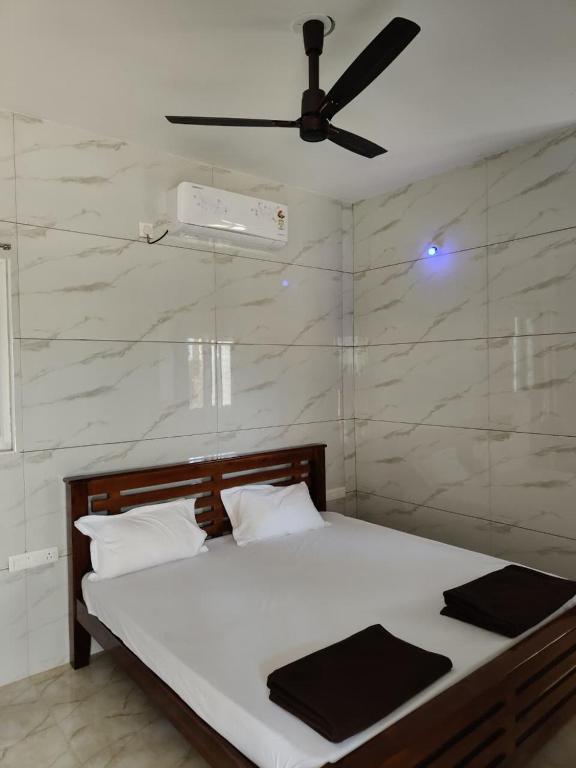 a bedroom with a bed with a ceiling fan at Eshwaraa Cottage in Palni