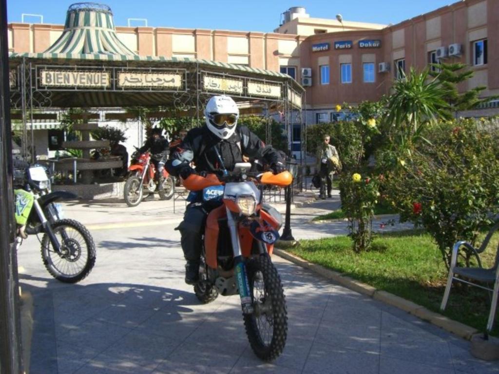 un homme à bord d'une moto sur un trottoir dans l'établissement Motel Paris Dakar, à Selouane