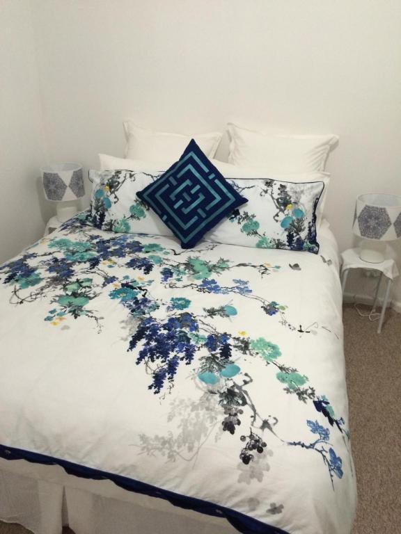 a bed with a blue and white comforter and pillows at Langley Cottage B&B in Coonabarabran