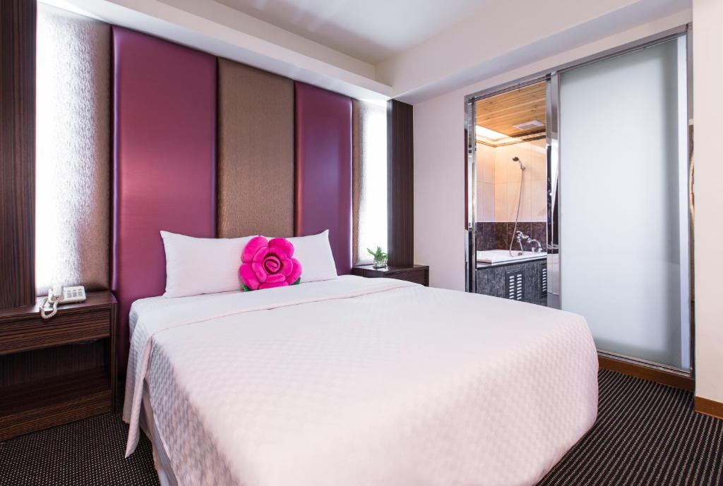 a bedroom with a white bed with a pink flower on it at Han She Hotel in Taipei