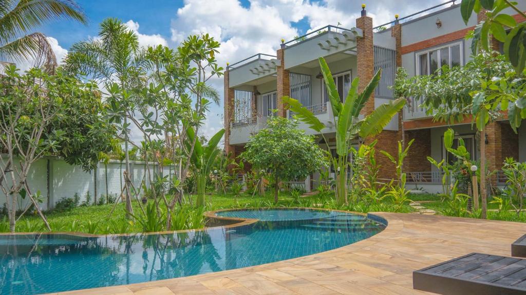 a villa with a swimming pool in front of a house at Hak Boutique Hotel in Siem Reap