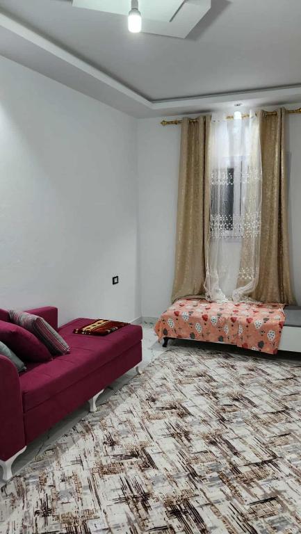 a living room with a purple couch and a bed at Studio Bayen in Douz