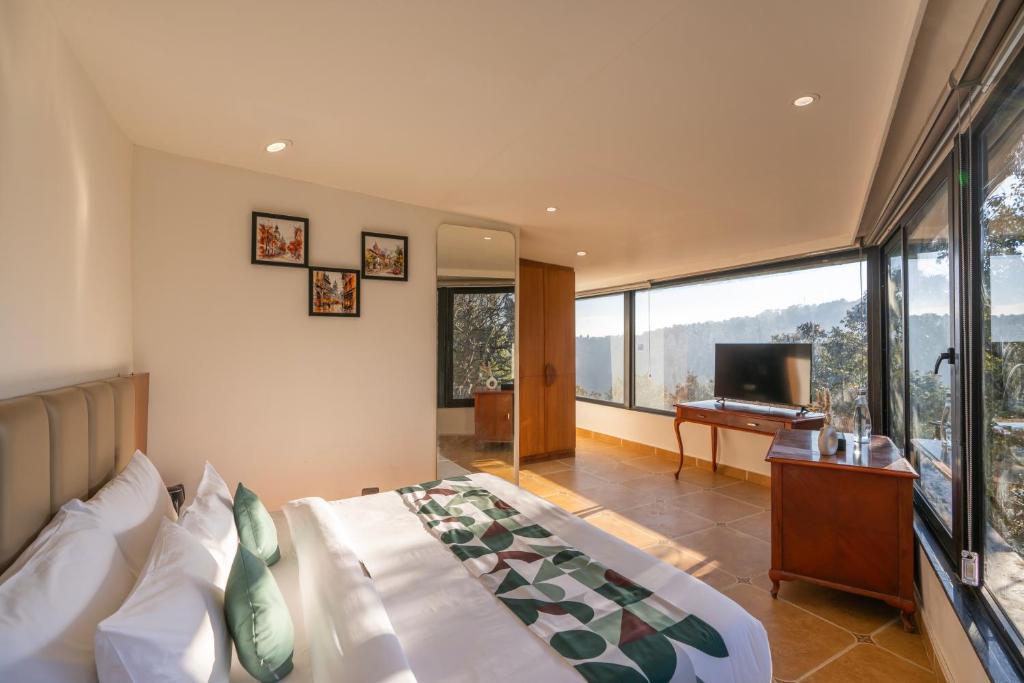 a bedroom with a large bed and a television at Moustache Select Nainital- Onsite Parking in Nainital
