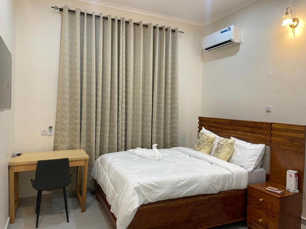 a bedroom with a bed and a desk and a window at Kibs Apartments in Dodoma