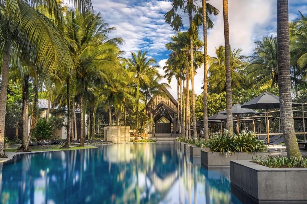 una piscina con palmeras frente a un edificio en Twinpalms Phuket en Surin Beach