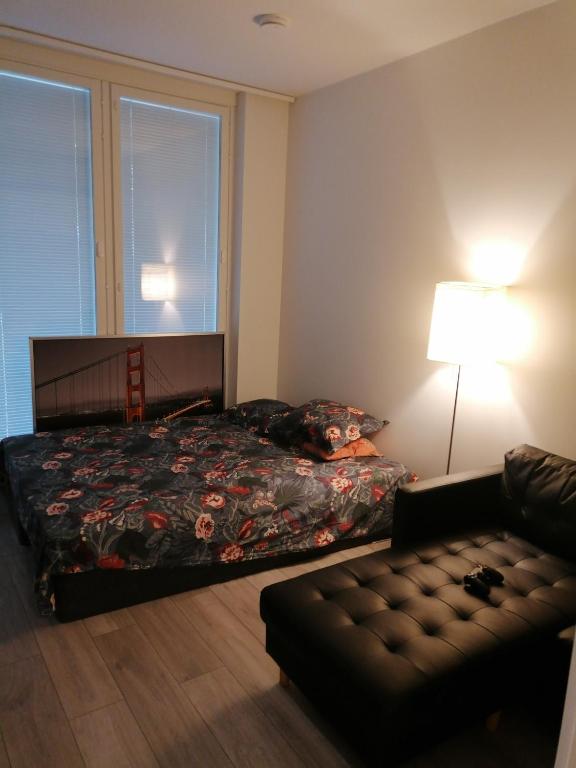 a bedroom with a bed and a couch and a lamp at Prince Palace in Vantaa