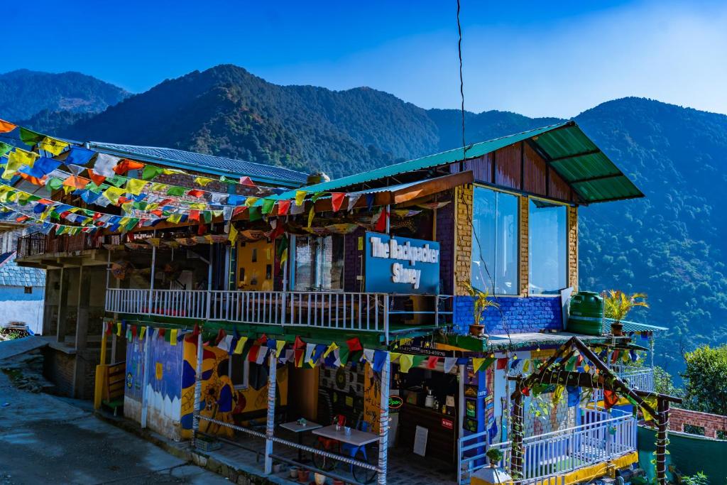 a building with prayer flags on the side of it at Backpacker Storey in Bīr