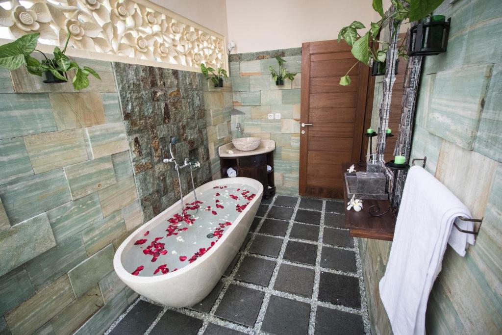 a bathroom with a bath tub with flowers on it at Junjungan Serenity Villas & Spa in Ubud