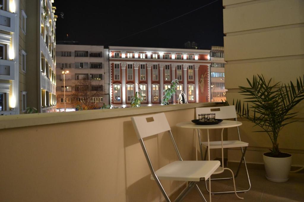 a balcony with two chairs and a table and a building at Lazarus Apartment in Skopje