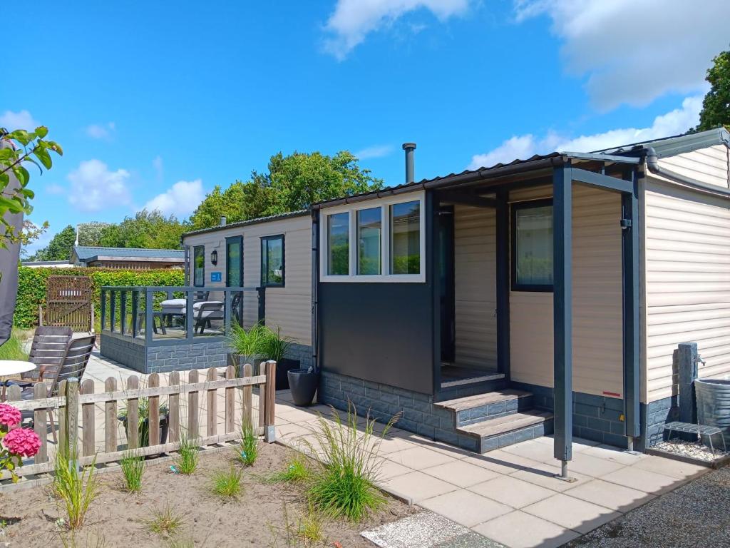a tiny house with a patio and a fence at 't Kotje Ouddorp in Ouddorp